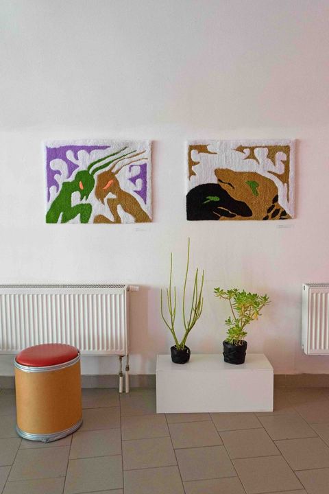 Dva bílé koberce s barevnými postavami na zdi galerie