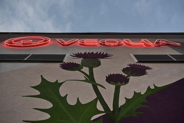 Bodlák pod svítícím neonovým logem Veolia